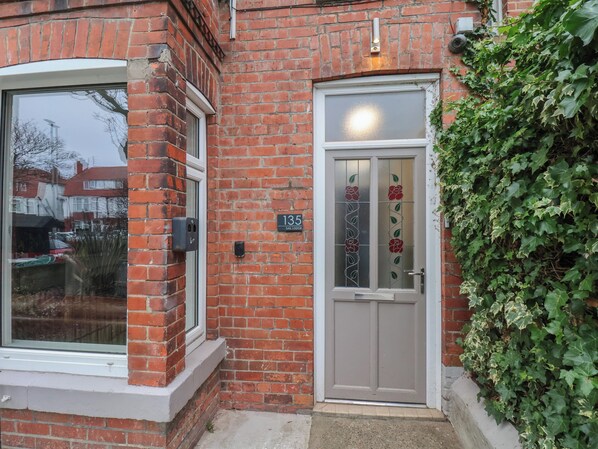 A brick building with a large window and a door with a number plate. - Sail Lodge (Scarborough)