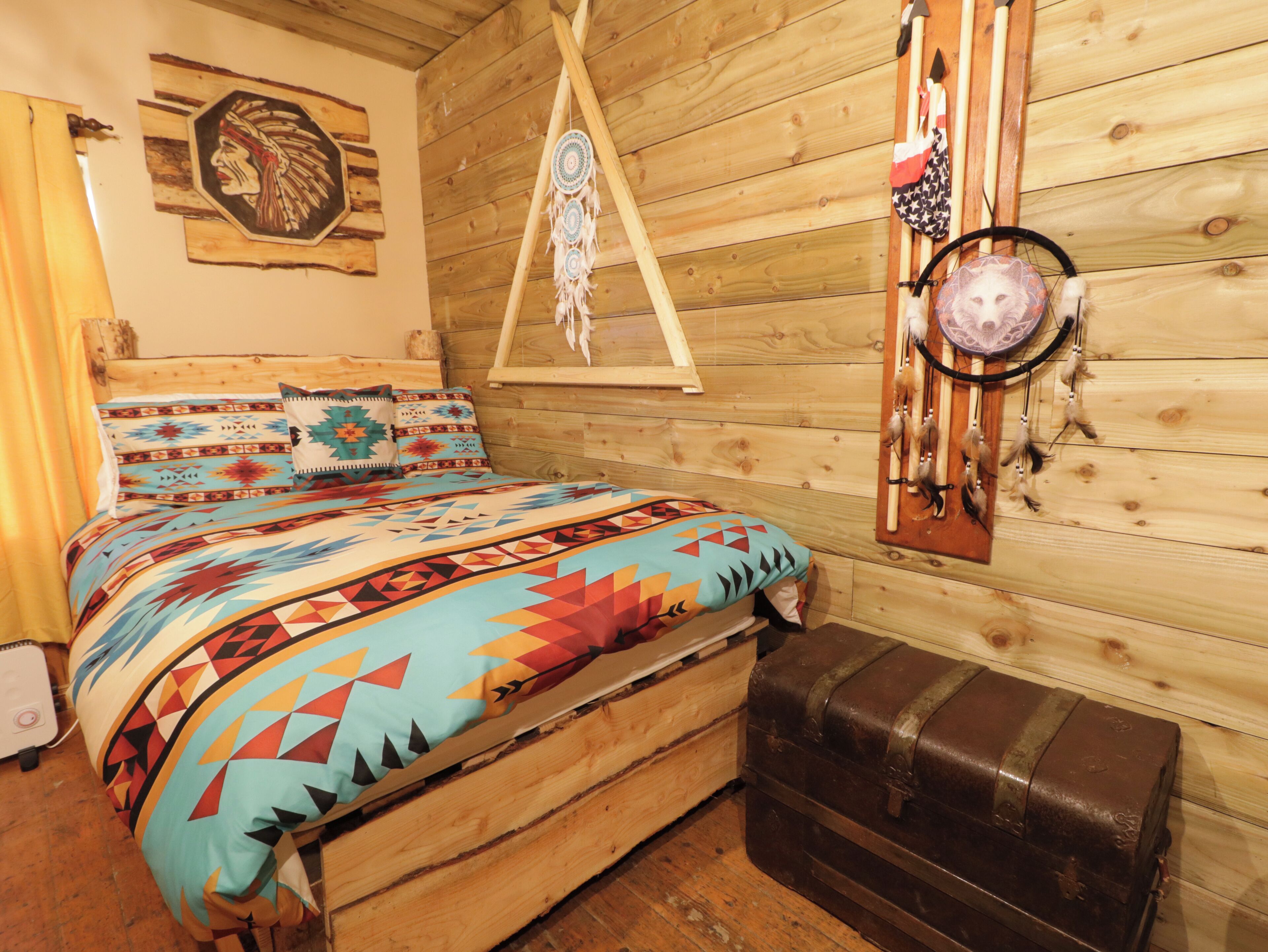 A cozy room with a wooden bed, a hanging dreamcatcher, and a wall-mounted dreamcatcher.