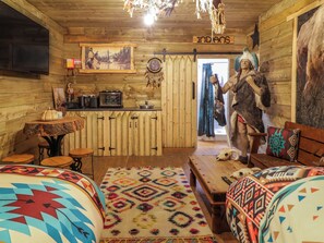 A rustic room with wooden walls, a large painting, a dreamcatcher, and a statue of a Native American figure. - Apache Falls Lodge (Limavady)