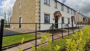 A modern two-story residential building with a stone facade and multiple windows. - Pear Tree Cottage (Preston)