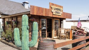 Un edificio rústico con fachada de madera, un letrero que dice 'Whiskey Creek' y un gran cactus al frente.
