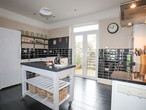 Una cocina moderna con una decoración en blanco y negro, horno empotrado y ventana con vistas a un jardín.