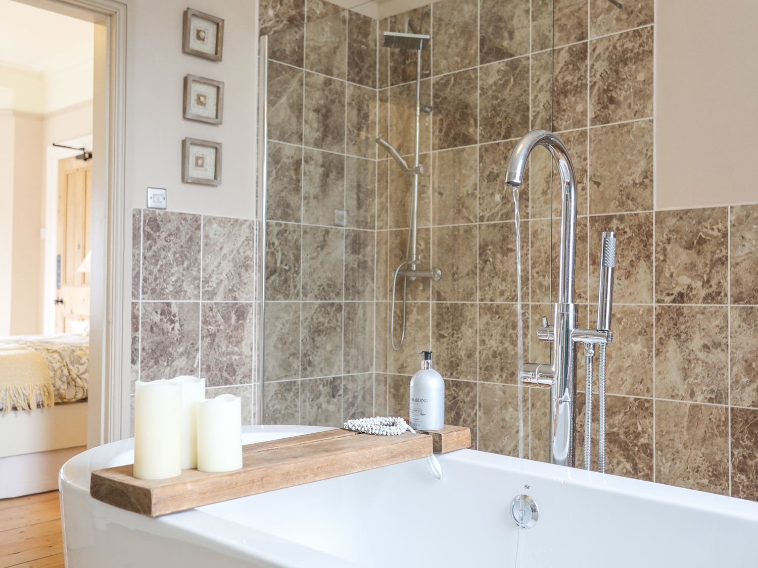 A modern bathroom with a freestanding bathtub, a handheld showerhead, and a wall-mounted faucet.