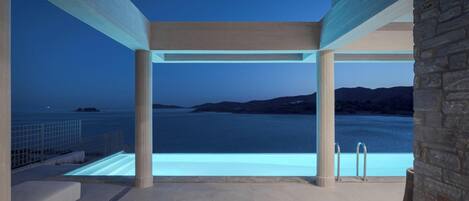 An infinity pool with a clear view of the sea and distant hills.