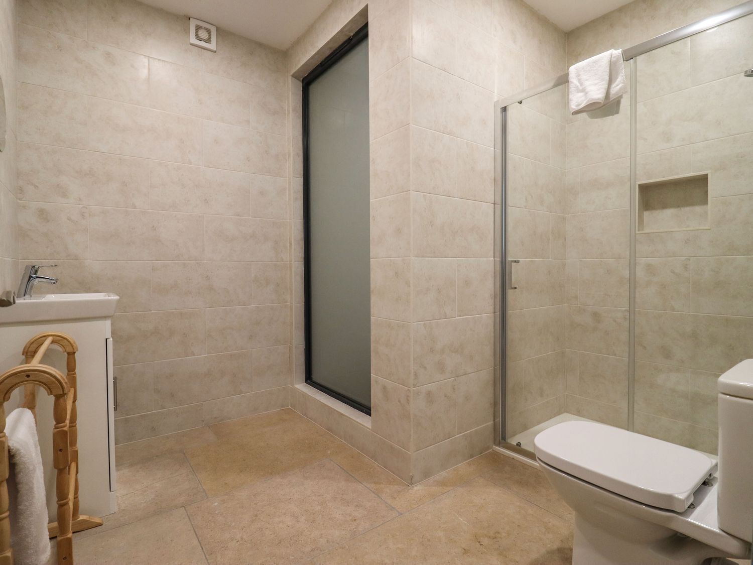 A bathroom with a shower, toilet, sink, and a towel rack.