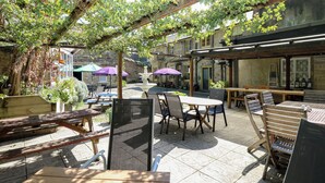 Un espace extérieur aménagé en terrasse, avec des tables et des chaises, une fontaine et des parasols.