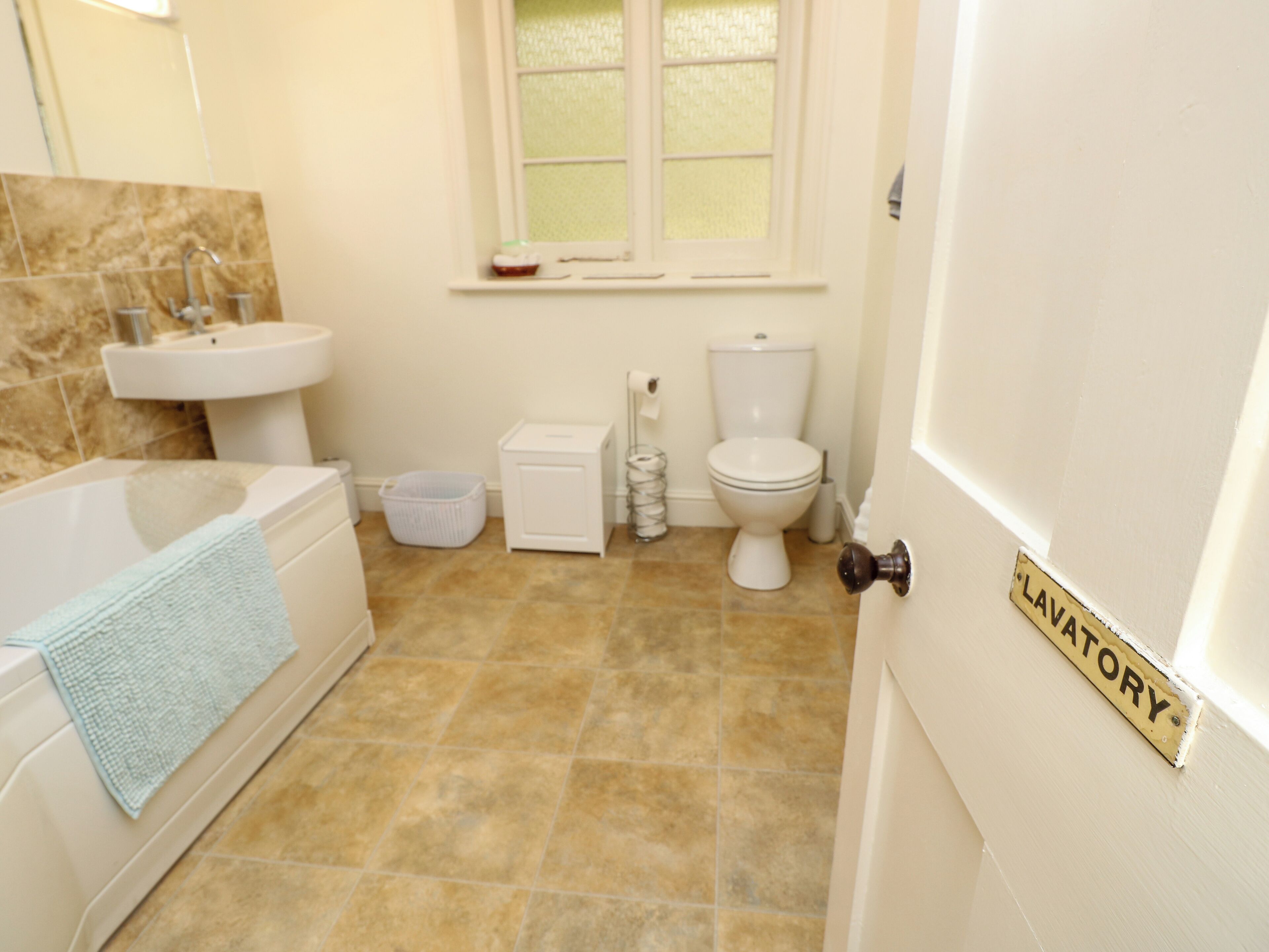 A bathroom with a bathtub, sink, toilet, and a door labeled "LAVATORY".