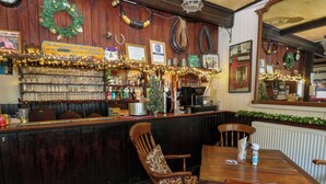 Un espace bar avec des meubles en bois, un sapin de Noël et diverses décorations.