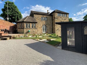 A stone building with a gravel driveway and a small wooden structure. - Dreamwood Cottage (Wakefield)