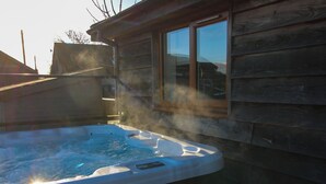 Ein Whirlpool neben einer Holzhütte mit einem Fenster.