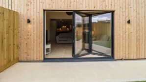 A modern building with a wooden exterior and a glass sliding door entrance. - Bears Court Barn 3 (Cheltenham)
