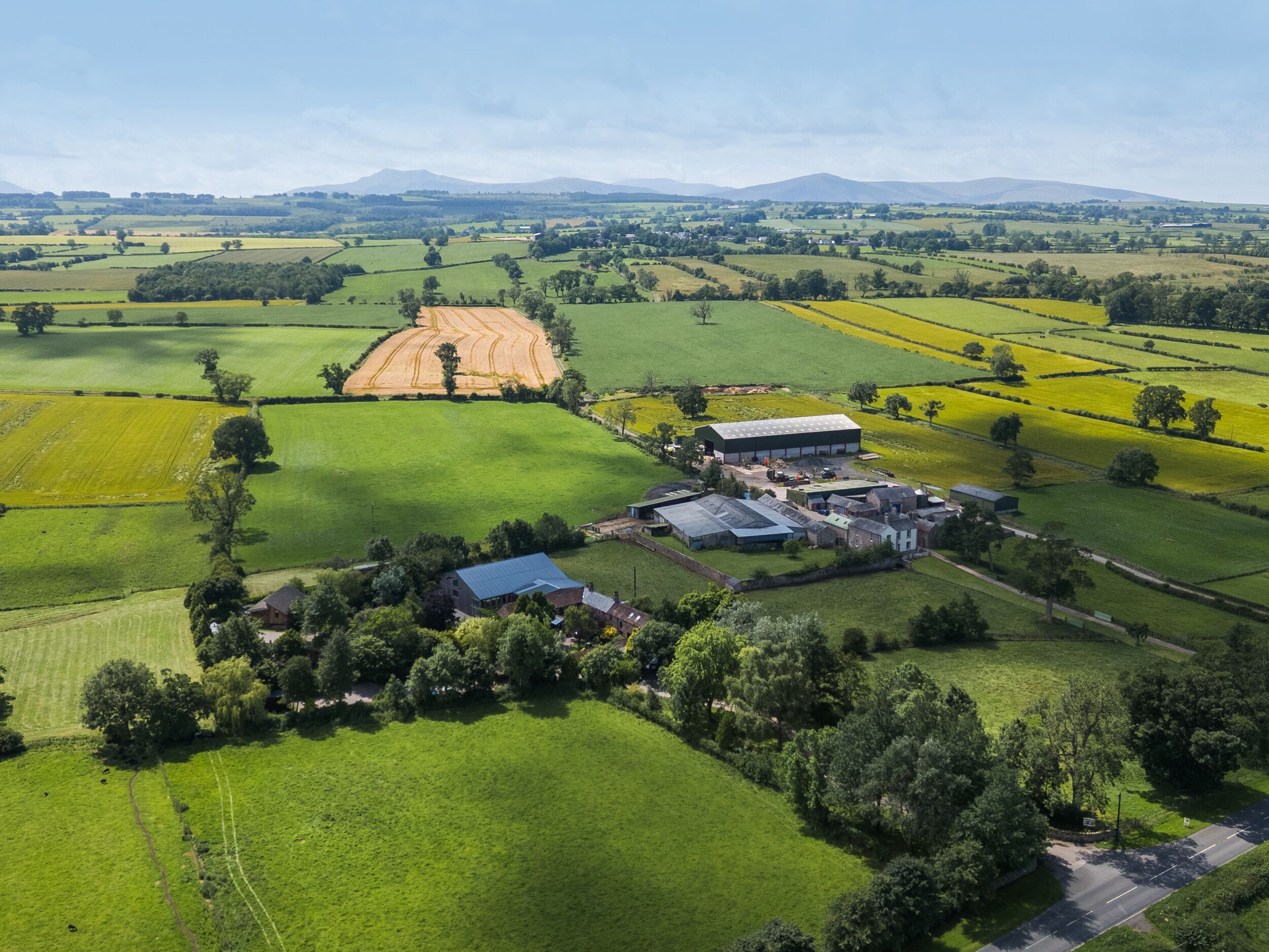 An aerial view of a rural property with fields, a farmhouse, and a large barn.