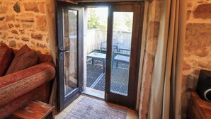 Ein Zimmer mit Steinwänden und einer Schiebeglas-Tür, die auf eine Terrassenanlage im Freien führt.