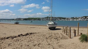 A sandy beach with a sailboat anchored near the shore. - Widemouth Bay (Bideford)
