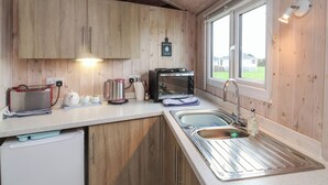 A compact kitchen with wooden cabinets, a toaster, a kettle, and a sink. - Widemouth Bay (Bideford)