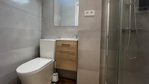 A modern bathroom with a toilet, sink, and shower. - Hostal Bernabeu (Madrid)