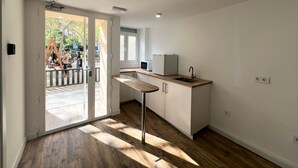 A modern kitchen with a wooden countertop, a sink, and a refrigerator. There is a sliding glass door leading to an outdoor area with a playground. - Hostal Bernabeu (Madrid)