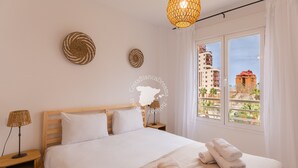 Une chambre d’hôtel avec un lit, une table de chevet, une lampe et une vue sur les immeubles par la fenêtre.