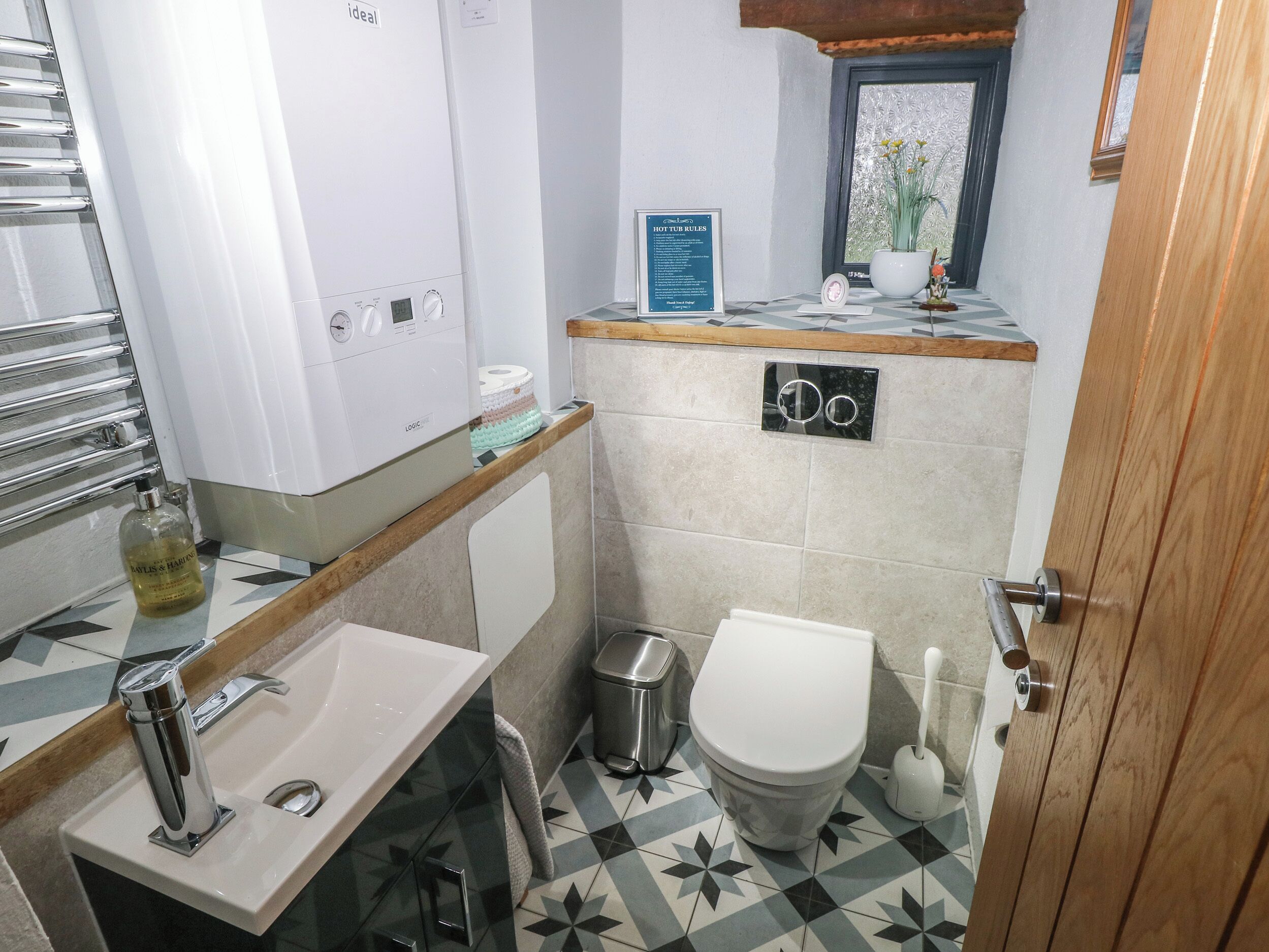 Et moderne badeværelse med toilet, vask, spejl og bruseområde.