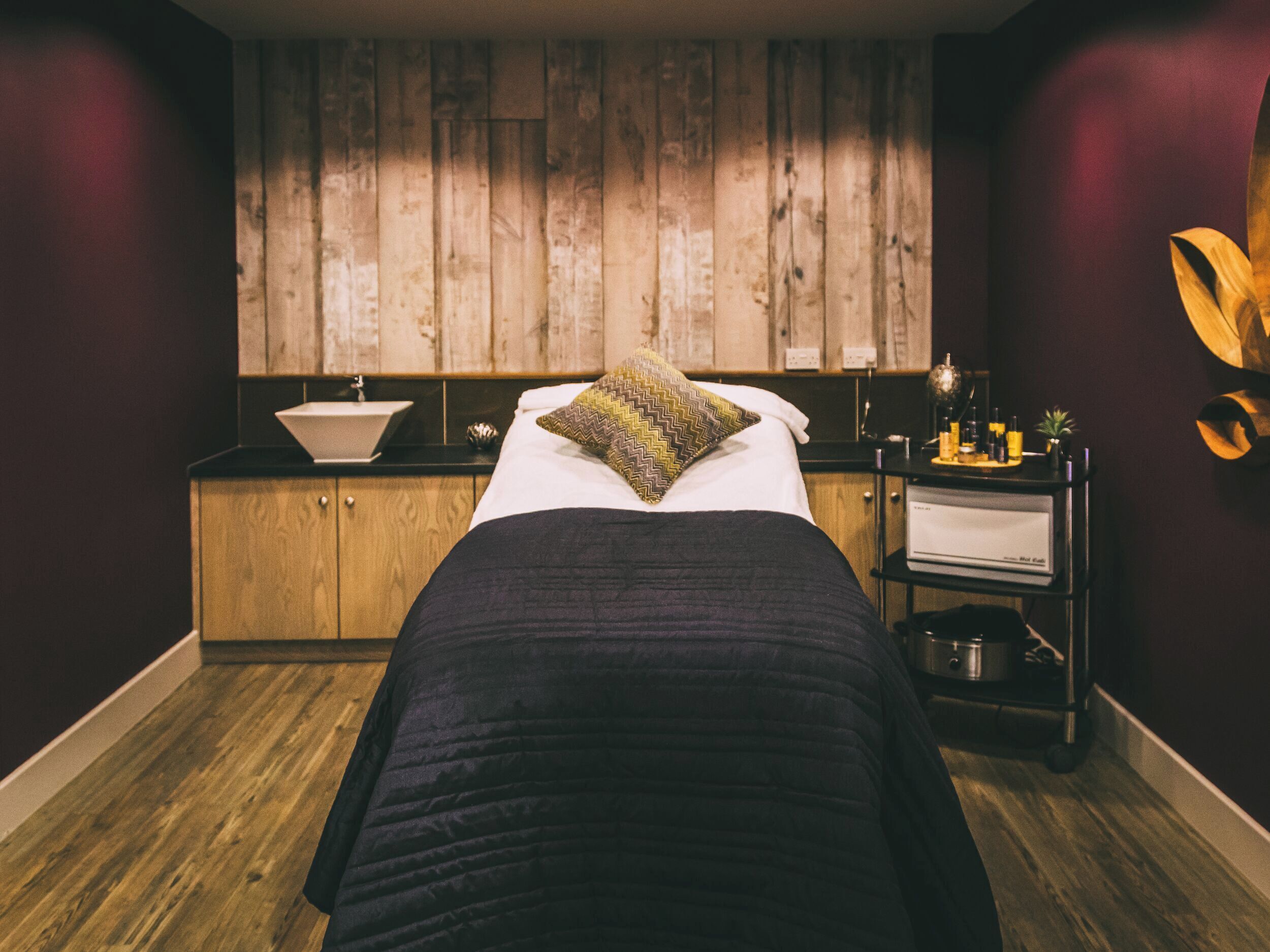 Ein Zimmer mit einem Bett, einer Holzvertäfelung, einem kleinen Waschbecken und einem Ablagefach mit Toilettenartikeln.