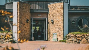 A building entrance with stone pillars, a brick pathway, and a circular window. - Una, Lodge 77 (St Ives)