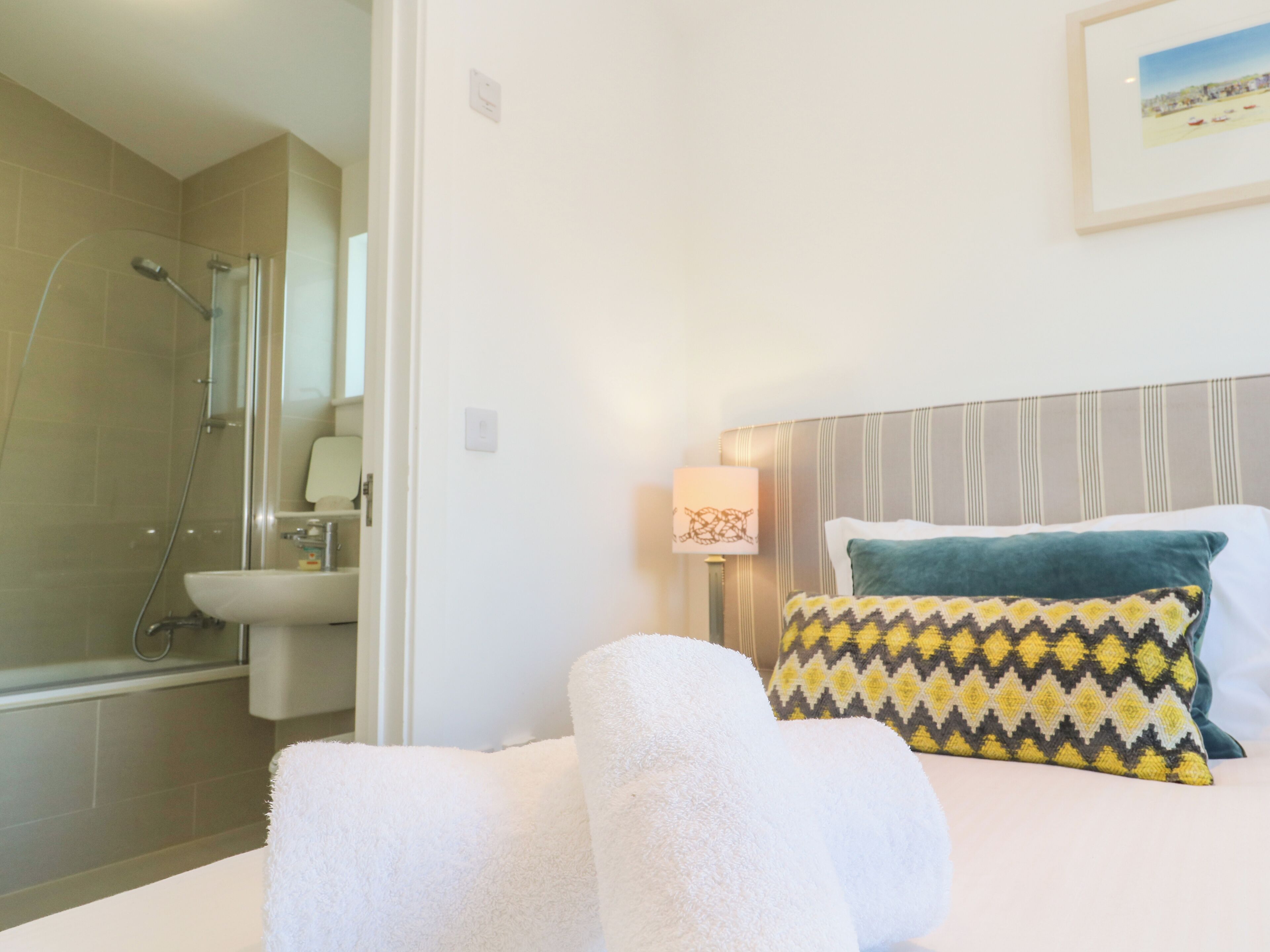 Une chambre d’hôtel équipée d’une douche, d’un lavabo, d’un lit avec des oreillers et d’une lampe fixée au mur.