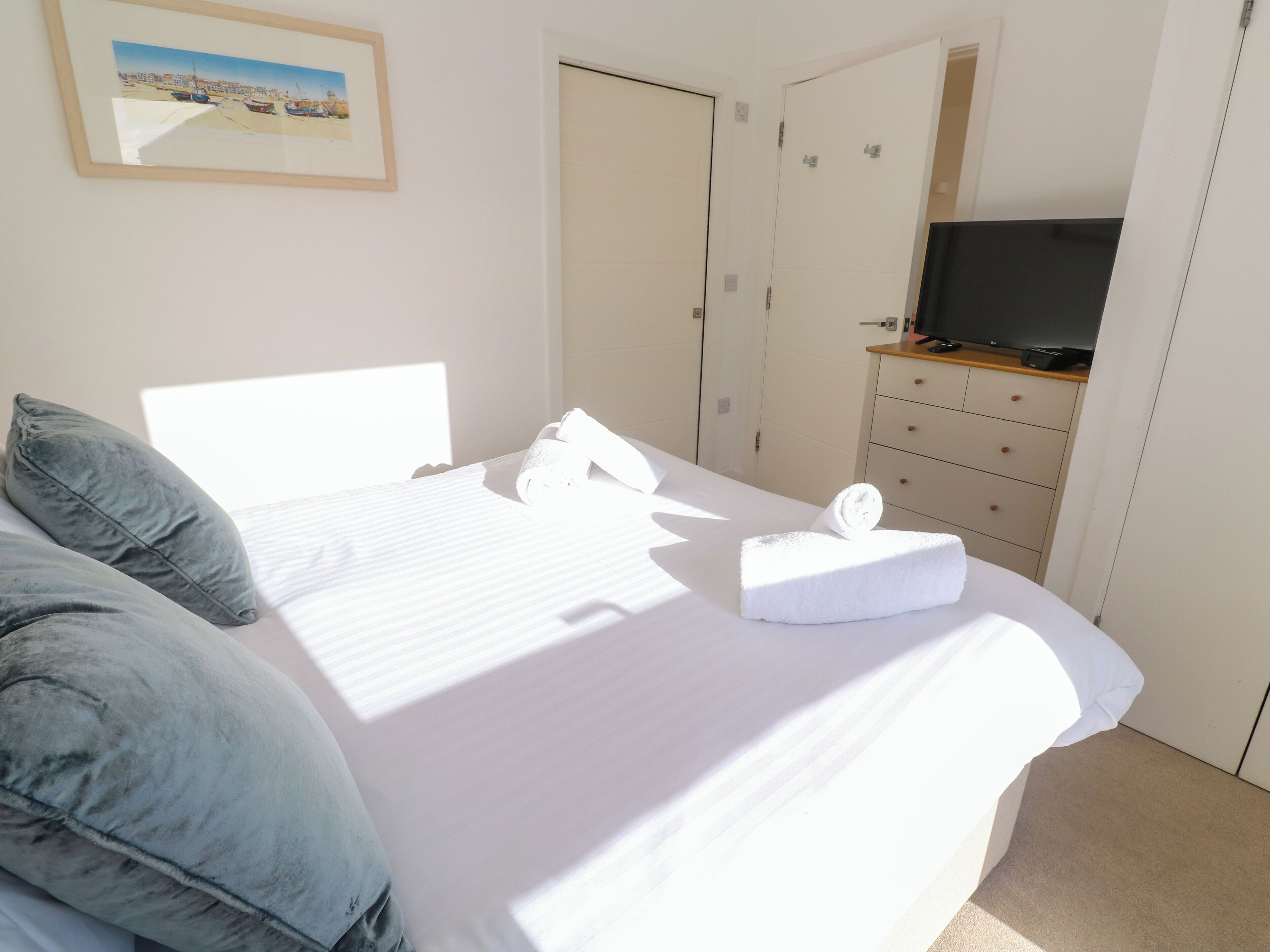 Una habitación de hotel con cama, almohadas, televisor y cómoda.