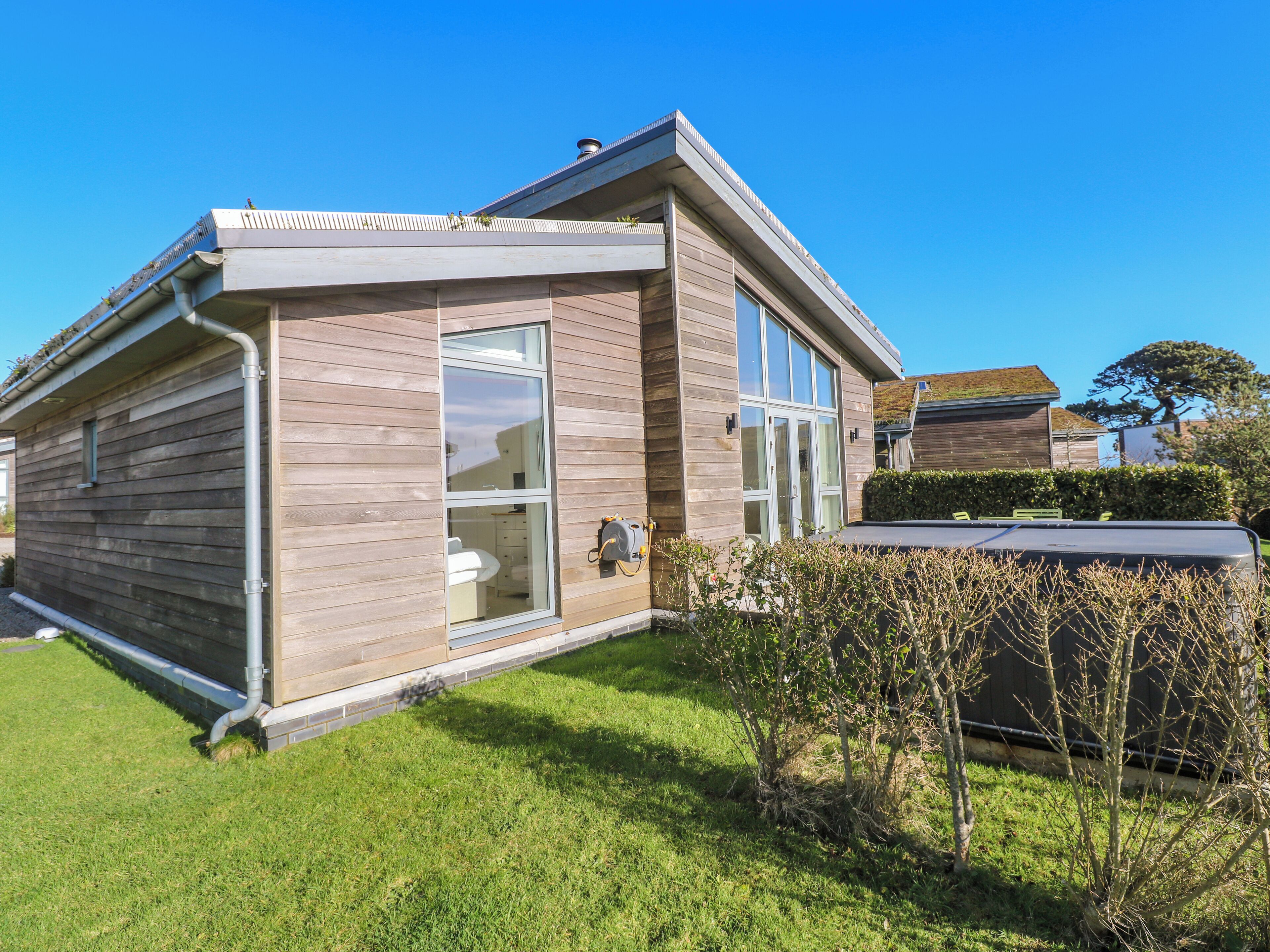 A modern house with a large window, a visible outdoor area, and a well-maintained lawn.
