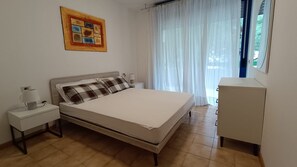 A bedroom with a bed, a nightstand, a lamp, a dresser, and a painting on the wall.