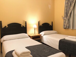 A hotel room with two single beds, a nightstand with a lamp, and a window with curtains. - Serinamar - Aloha Gardens (Marbella)