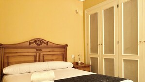 A neatly made bed with white linens and a folded towel, a wooden headboard, and a wardrobe with a mesh design. - Serinamar - Aloha Gardens (Marbella)
