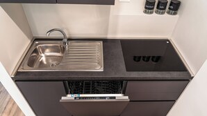 A compact kitchen with a stainless steel sink, a dishwasher, and a black countertop. - Beachside getaway in Bibione (Bibione)