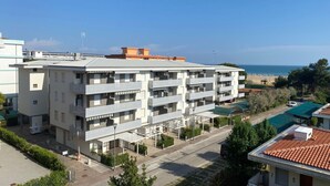 A multi-story residential building with balconies, a parking area, and a view of the sea. - Beachside getaway in Bibione (Bibione)