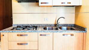 Une cuisine avec des meubles en bois, un plan de travail en granit, un évier en acier inoxydable et une cuisinière à gaz.
