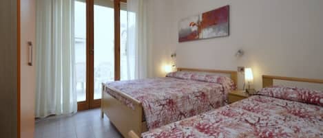 Habitación de hotel con dos camas, un ventanal con cortinas, un cuadro en la pared y piso de baldosas.