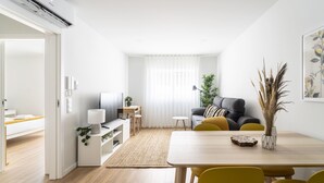 A modern living room with a sofa, a dining table, and a TV. - Forum Apartments II by House and People (Braga)