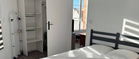 Een slaapkamer met een bed, een kast en een raam.