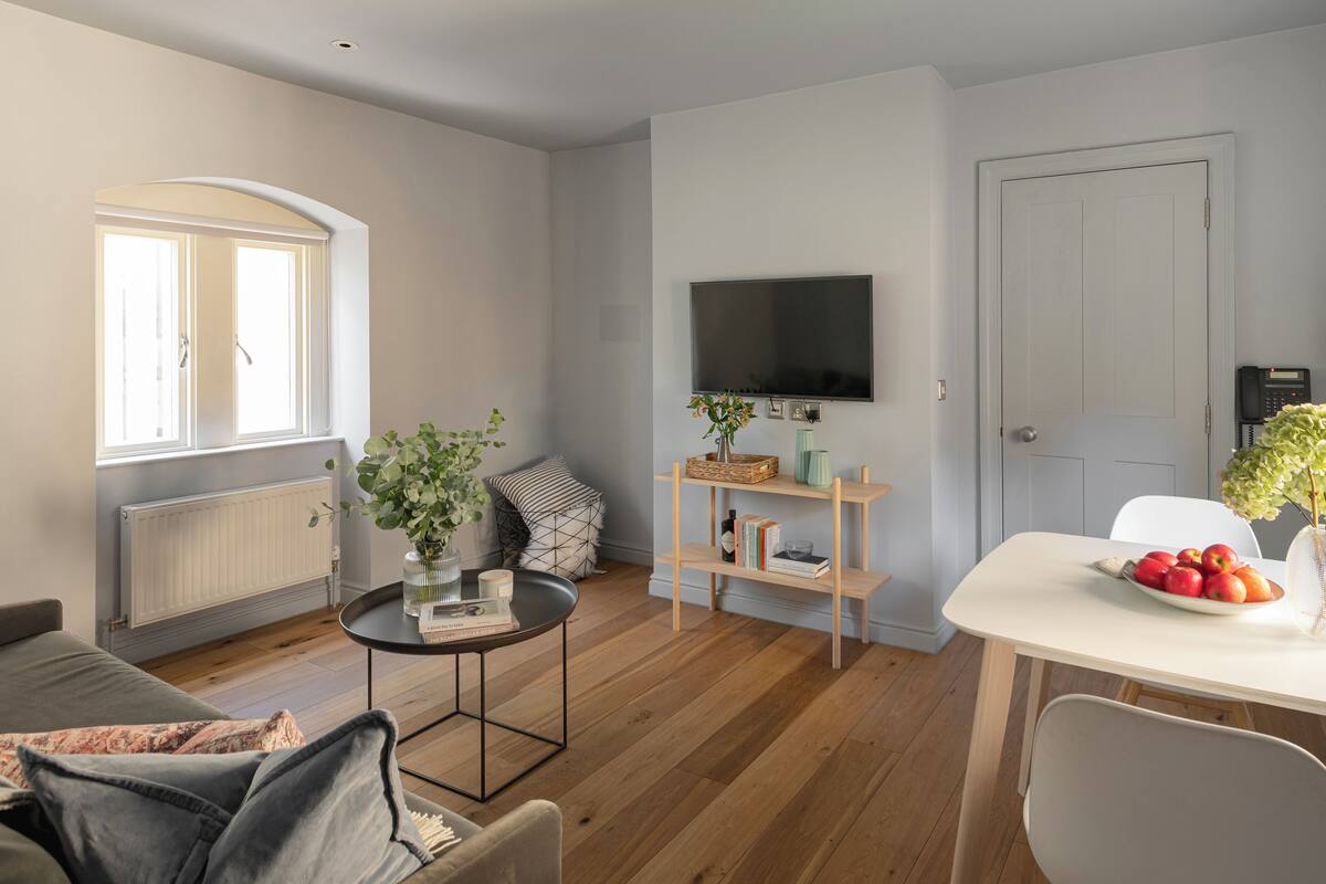 A modern living room with a sofa, coffee table, and a dining area with a table and chairs.