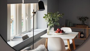 A cozy reading nook with a white table, a floor lamp, and a vase of flowers. - St Catherine's Hospital - Bath (Bath)
