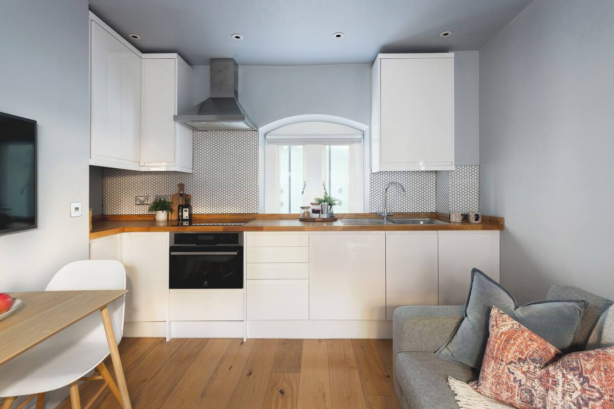A modern kitchen with white cabinetry, a wooden countertop, and a built-in oven.