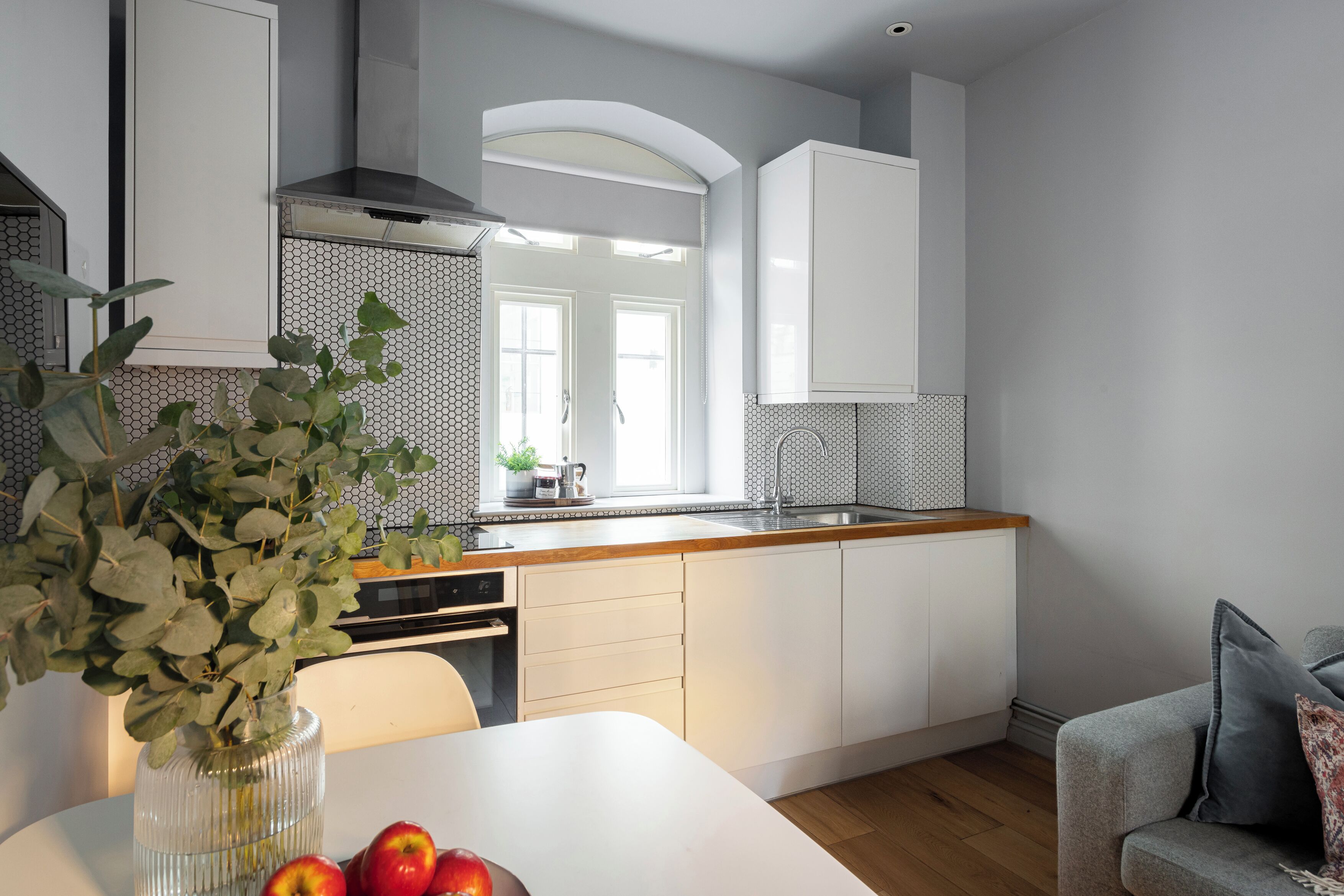 Una cucina moderna con mobili bianchi, un piano di lavoro in legno e un'area pranzo con tavolo e sedie.