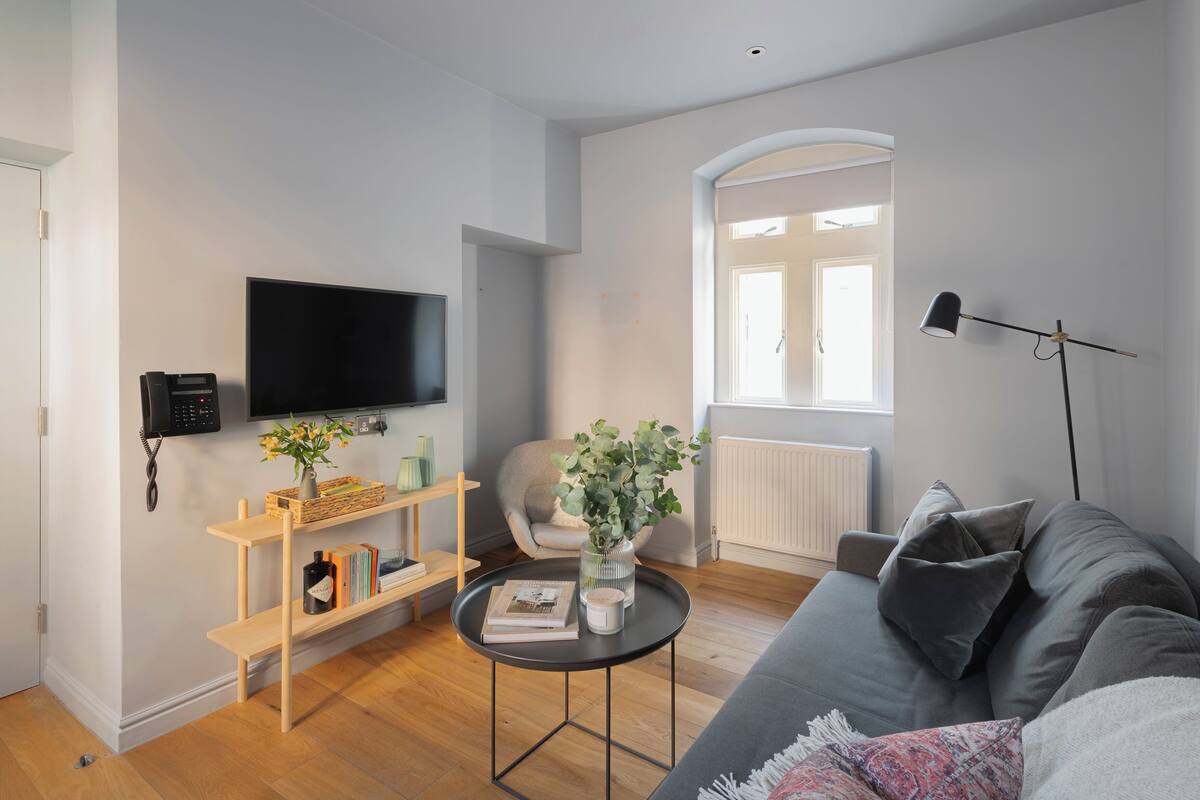 A modern living room with a flat-screen TV, a sofa, a coffee table, and a bookshelf.