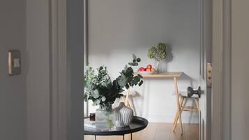 Een kamer met een ronde tafel, een klein krukje, een potplant en een plank met appels.