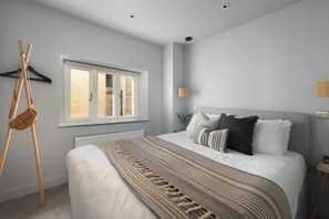 A bedroom with a large bed, a window, a hanging light fixture, and a radiator. - St Catherine's Hospital - Bath (Bath)