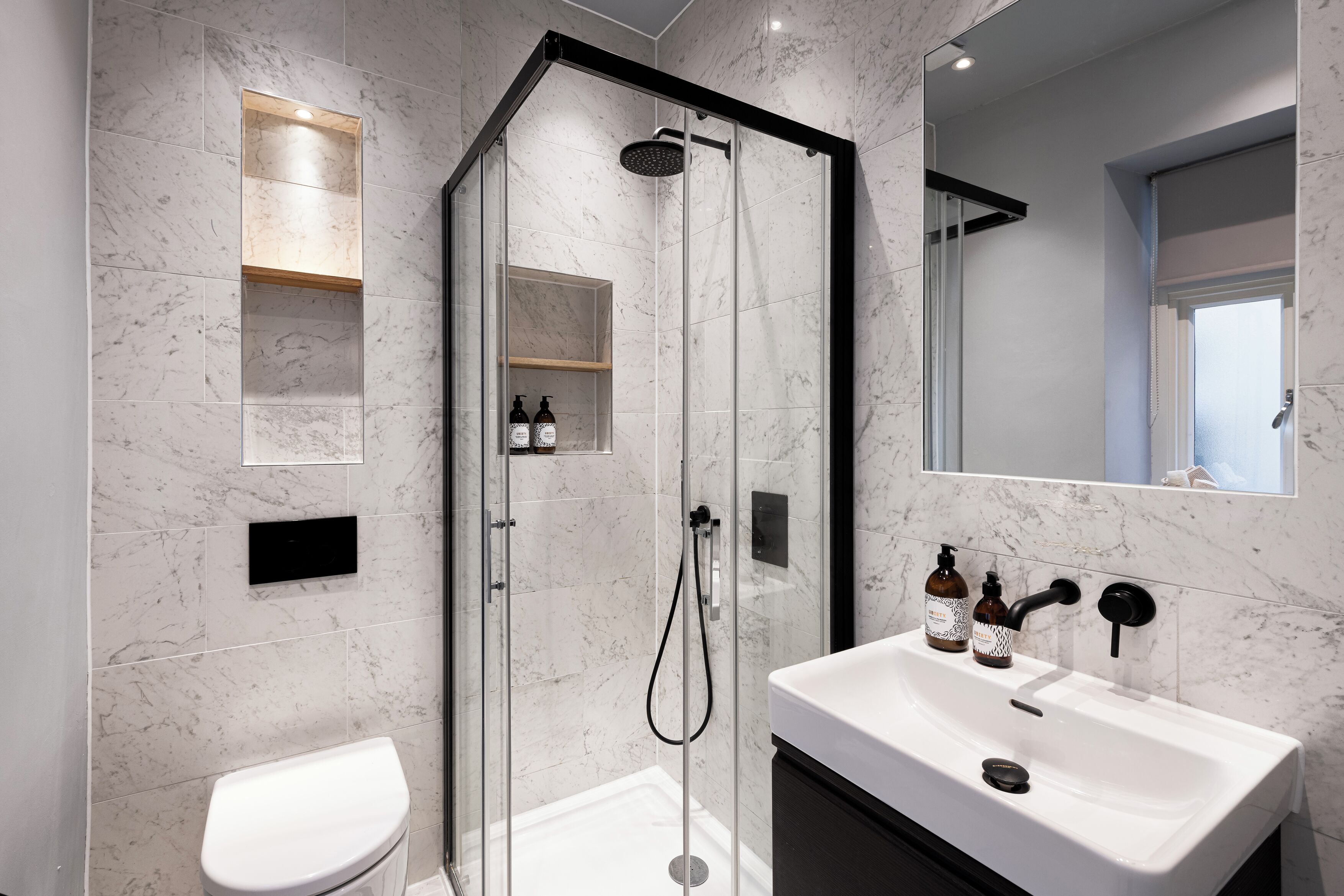 A modern bathroom with a glass-enclosed shower, a white sink, and a toilet.