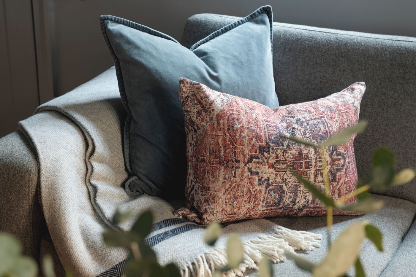 A sofa with two pillows, one plain and one with a patterned design.