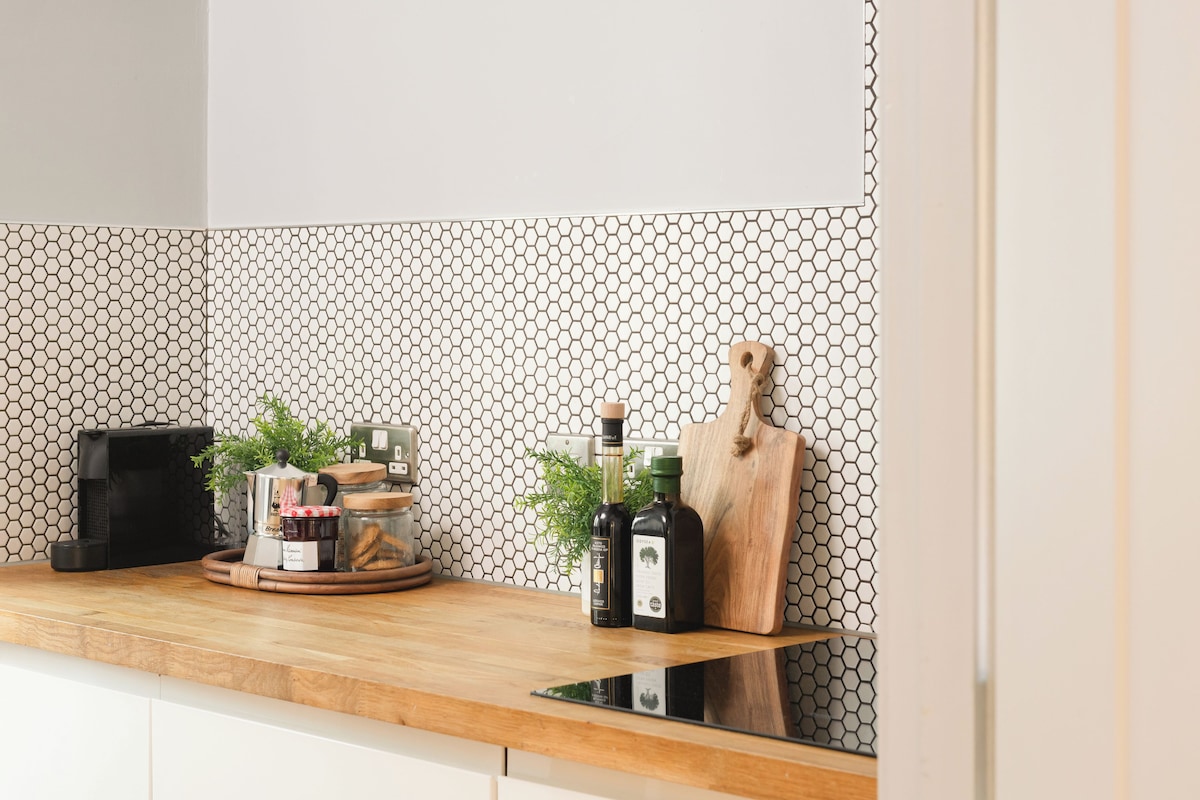 A kitchen with a wooden countertop, a coffee maker, a cutting board, and a plant.