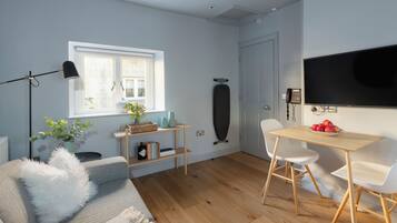 Ein modernes Wohnzimmer mit einer Couch, einem Couchtisch, einem Fernseher und einem Essbereich mit Stühlen.