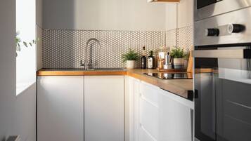 A modern kitchen with white cabinets, a wooden countertop, a stainless steel sink, and a built-in oven.