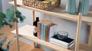 Uma prateleira de madeira com uma cesta trançada, livros, uma garrafa e vasos decorativos.